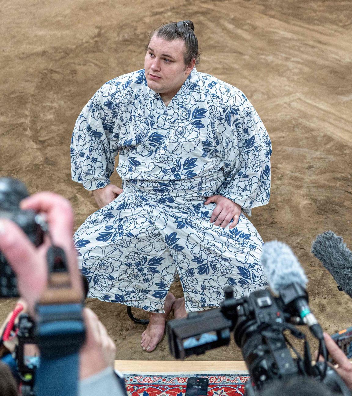 Der ukrainische Sumo-Ringer Aonishiki. Er sitzt und wird von Paperazzis fotografiert.