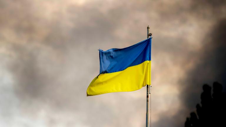 Ukrainische Flagge weht vor Rauch