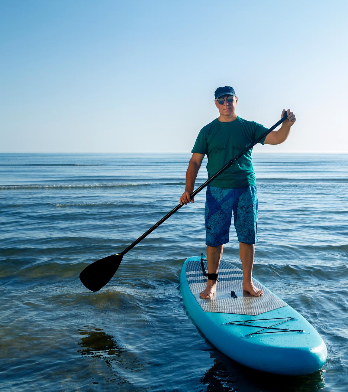 En Mann steht auf einem SUP und hält ein Paddel in der Hand.