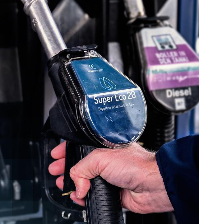 Eine Hand greift nach einem Zapfhahn, mit dem E20-Benzin getankt werden kann.