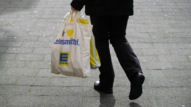 Ein Mann läuft in Düsseldorf am 25.02.2022 die Straße entlang und hält zwei Einkaufstüten in der Hand.