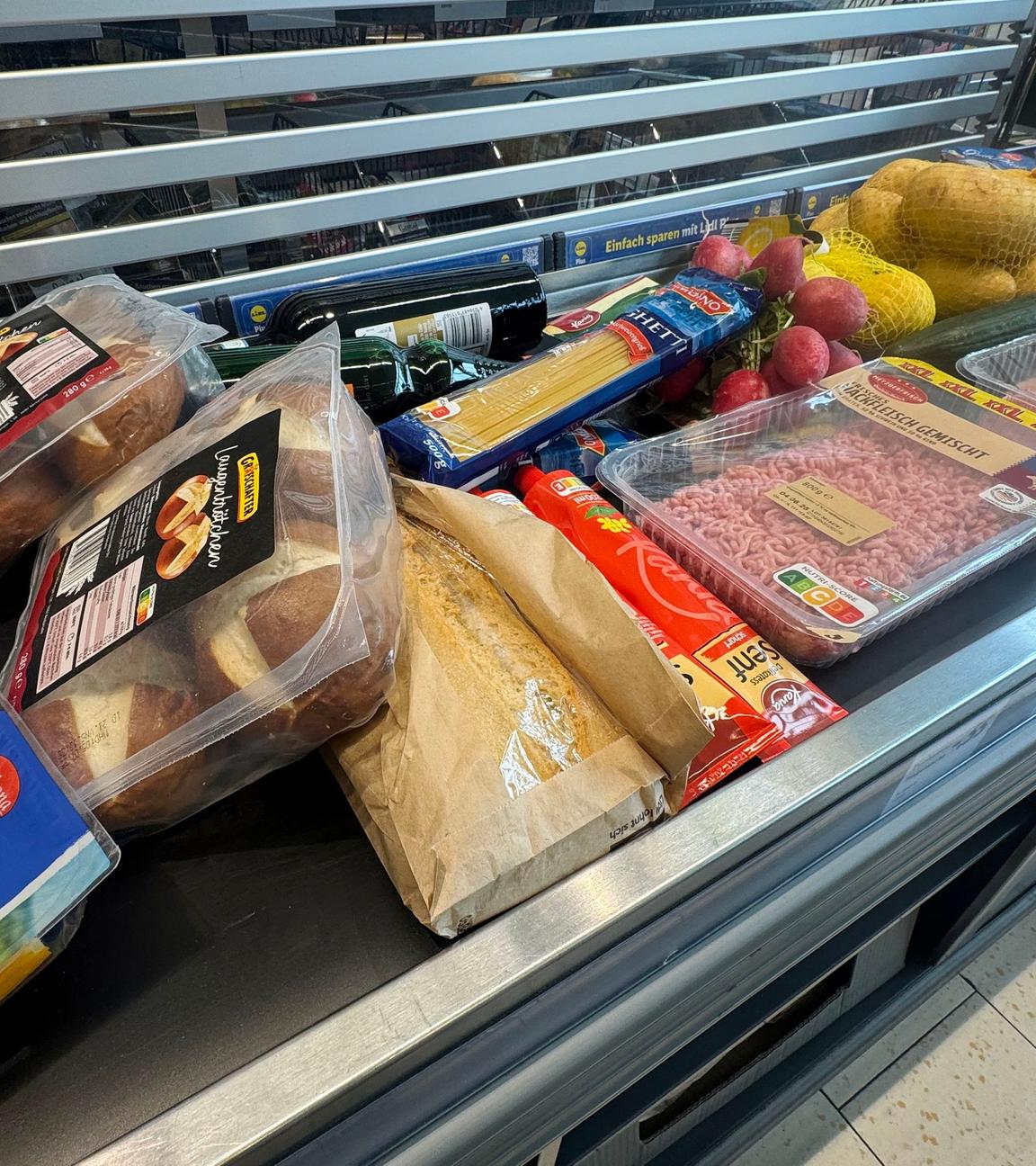 Lebensmittel liegen auf einem Kassenband an einer Supermarktkasse.