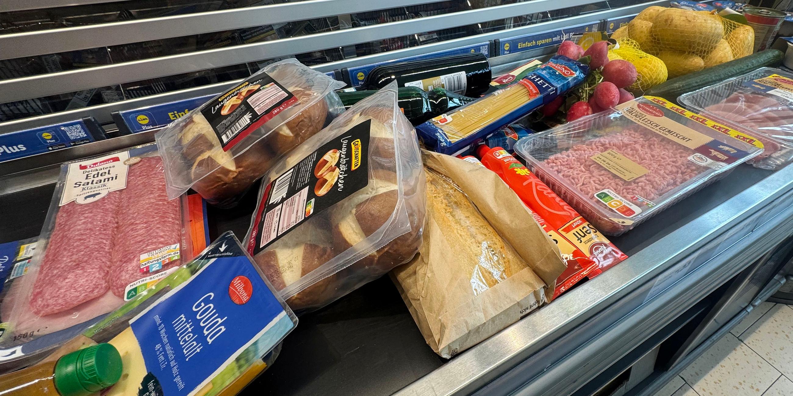 Lebensmittel liegen auf einem Kassenband an einer Supermarktkasse.