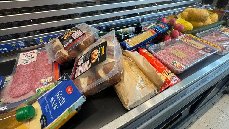 Lebensmittel liegen auf einem Kassenband an einer Supermarktkasse.