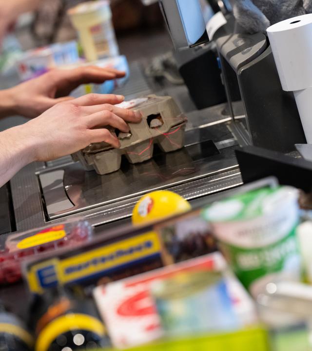  Ein Kassierer scannt in einem Supermarkt an der Kasse die Produkte.