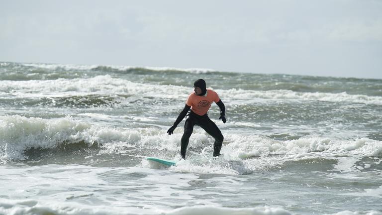 Ein Surfer steht auf dem offenen Meer in Dänemark auf seinem Surfbrett.