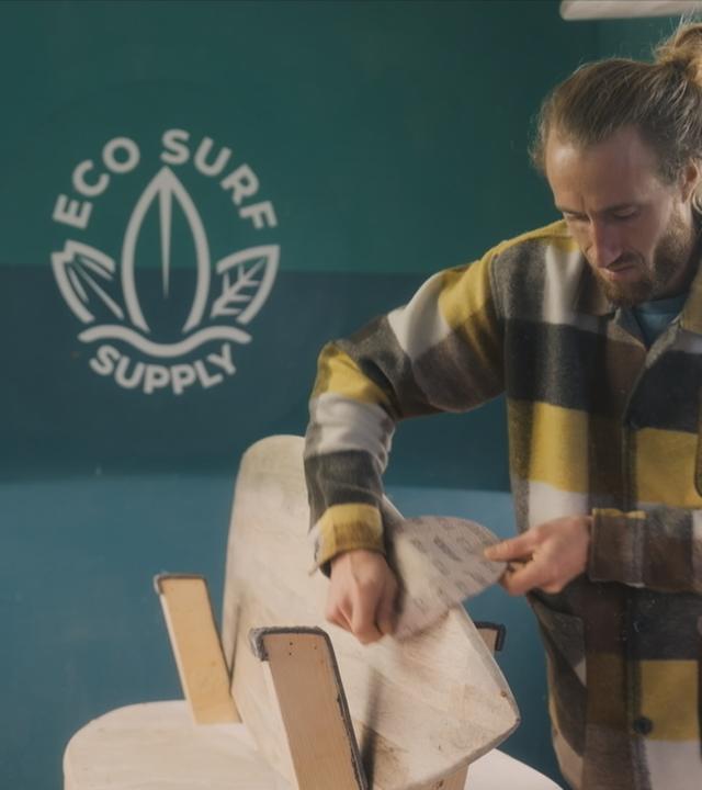 Ein Mann arbeitet an einem Surfbrett aus Holz