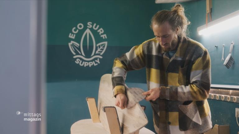 Ein Mann arbeitet an einem Surfbrett aus Holz