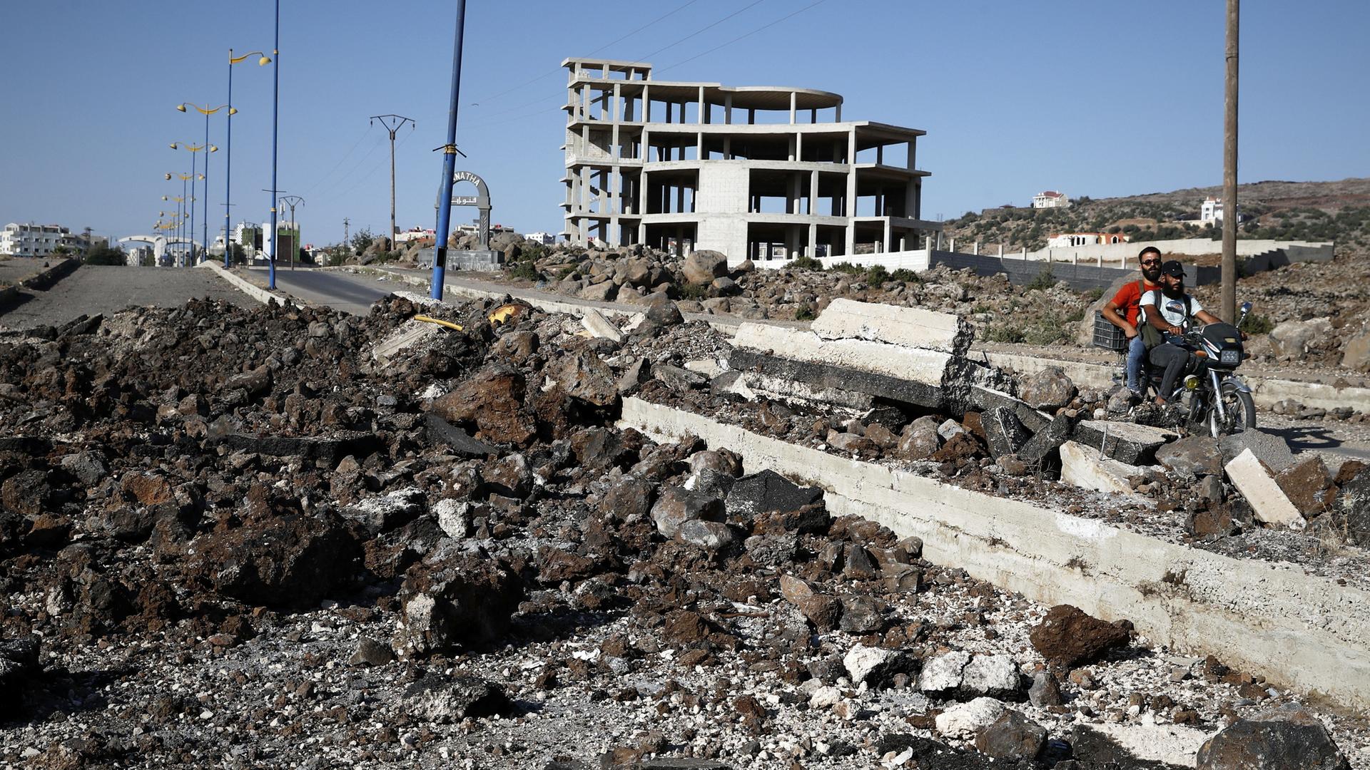 Drusische Milizionäre fahren auf einem Motorrad an der Hauptstraße außerhalb von Suweida an der Stelle vorbei, an der die israelische Armee Mitte Juli einen Angriff verübt haben soll.