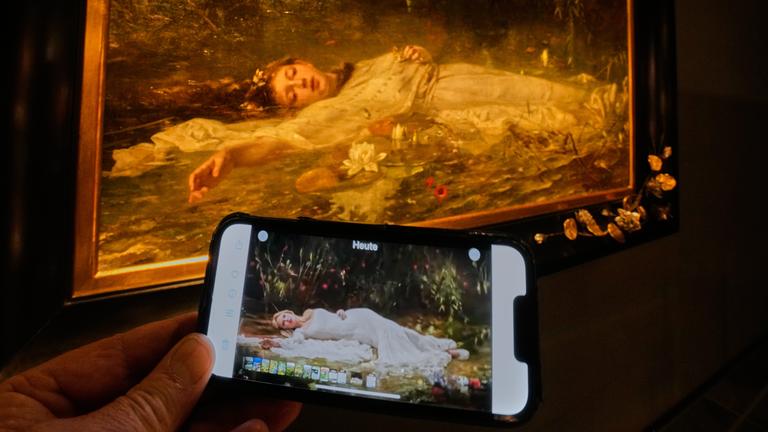 The opening part of Taylor Swift's video "The Fate of Ophelia" is displayed on a mobile phone in a museum showing a painting by Art Nouveau painter Friedrich Heyser showing Ophelia, a Shakespeare Character, in Wiesbaden, Germany