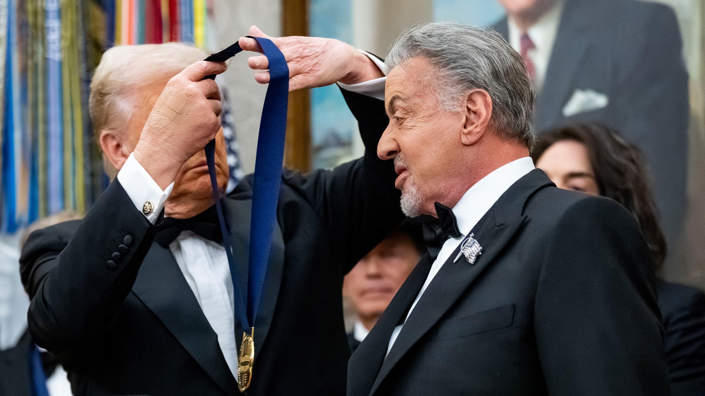 US-Präsident Donald Trump überreicht am 06.12.2025 dem Schauspieler Sylvester Stallone, der 2025 vom Kennedy Center geehrt wird, während einer Zeremonie im Oval Office des Weißen Hauses in Washington eine Medaille.