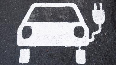 Symbol eines E-Autos auf eienr Straße.