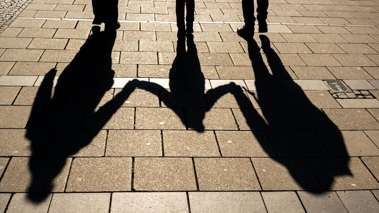 Die Schatten von zwei Erwachsenen und einem Kind fallen auf den Asphalt
