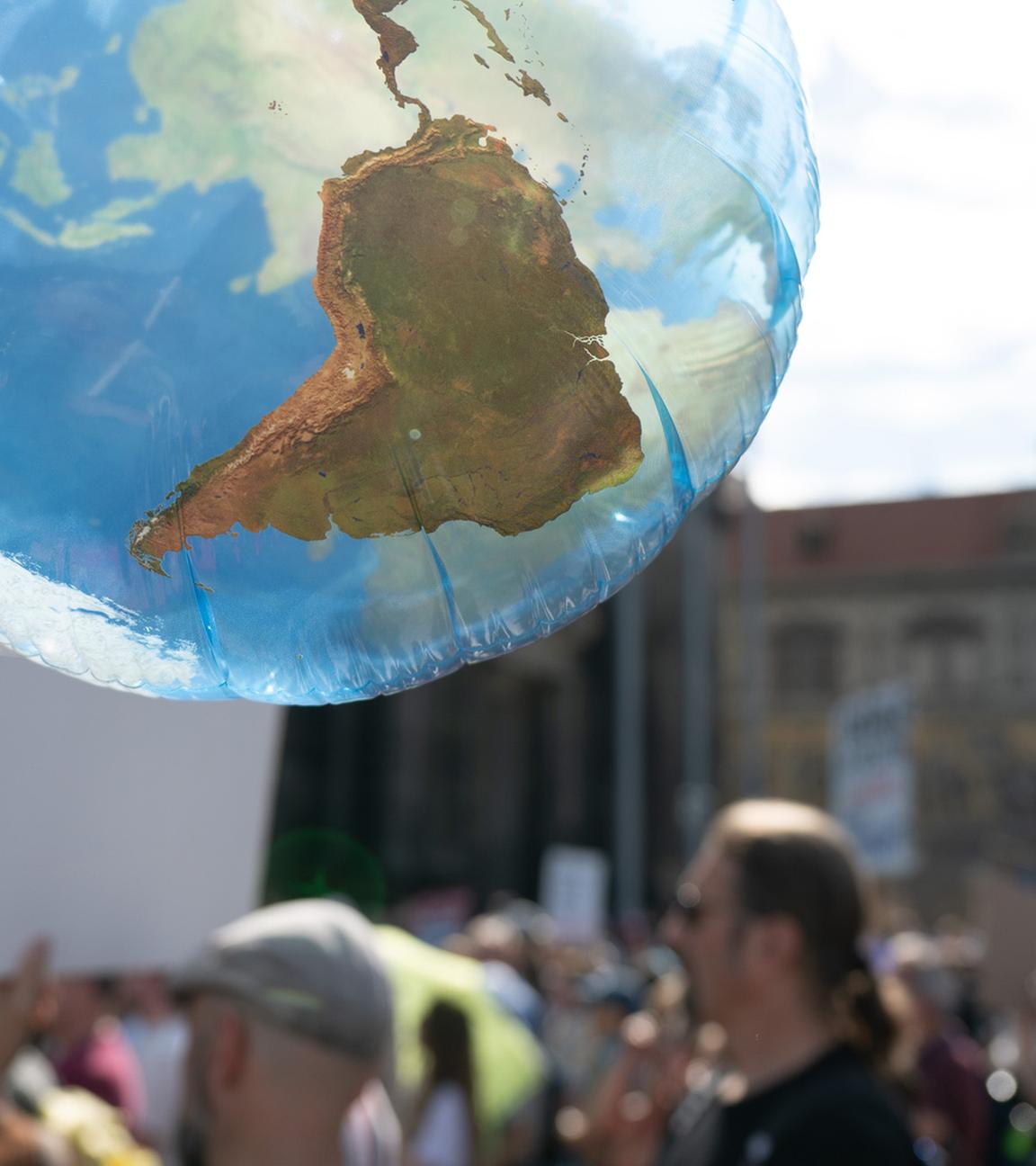Teilnehmer eines Klimastreiks von Fridays for Future stehen auf dem Schlossplatz in Dresden hinter einem Ballon in Form einer Weltkugel. (Archiv)