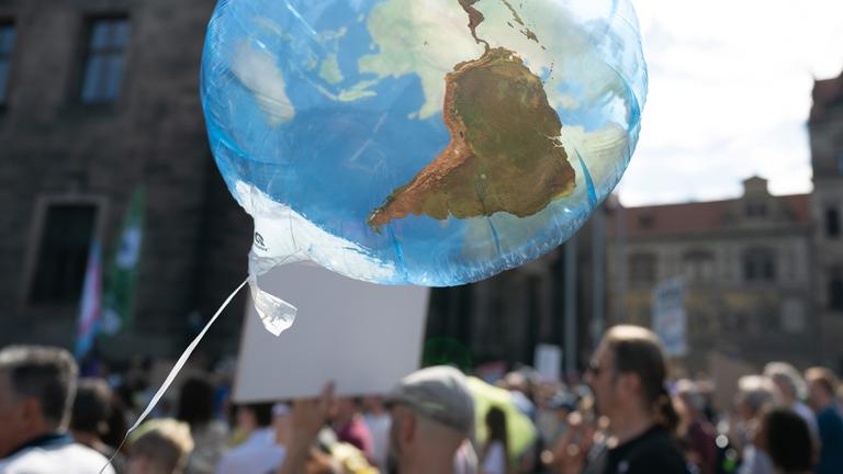 Teilnehmer eines Klimastreiks von Fridays for Future stehen auf dem Schlossplatz in Dresden hinter einem Ballon in Form einer Weltkugel. (Archiv)