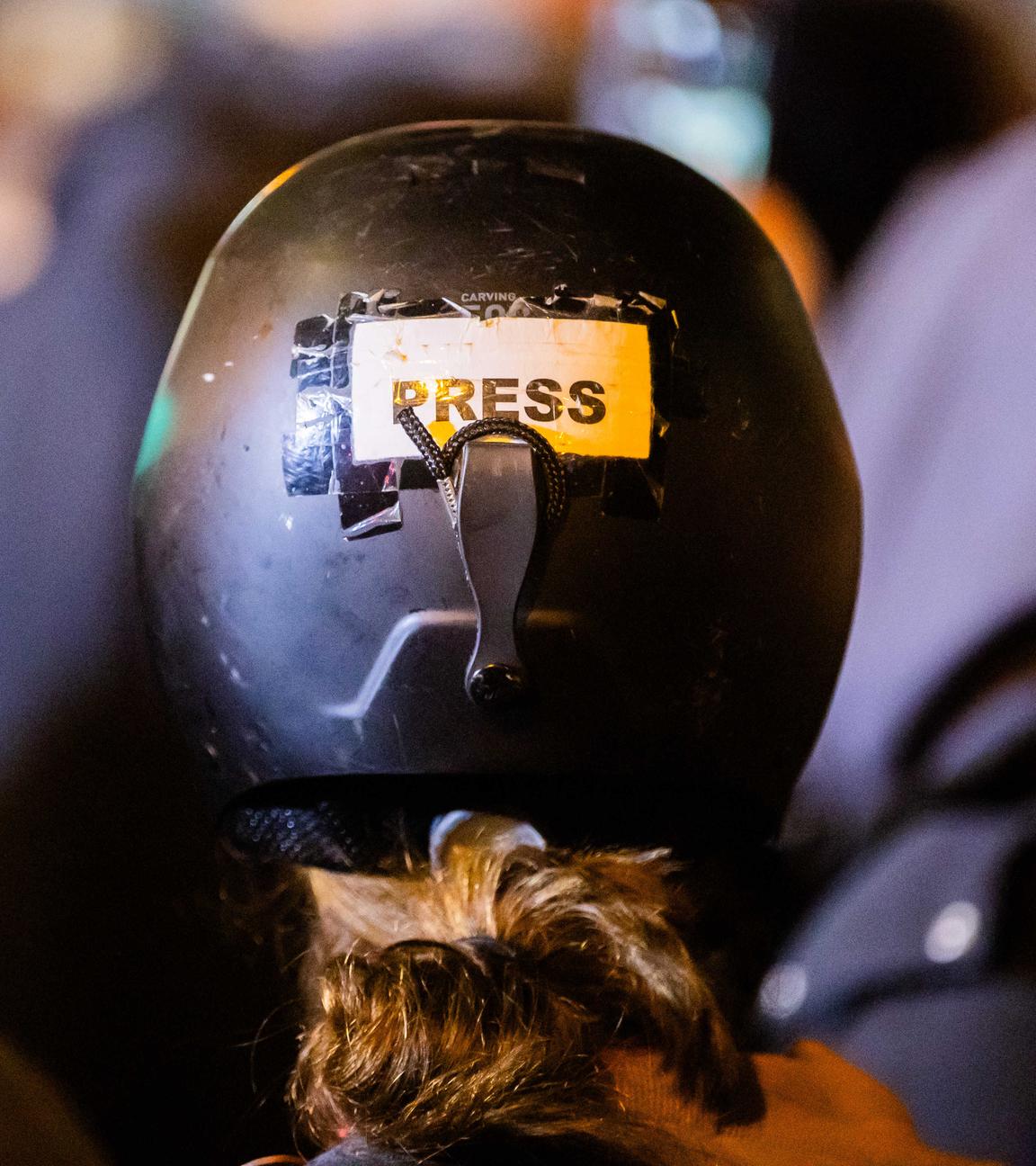 Eine Journalistin trägt einem Schutzhelm, auf dem "Press" zu lesen ist