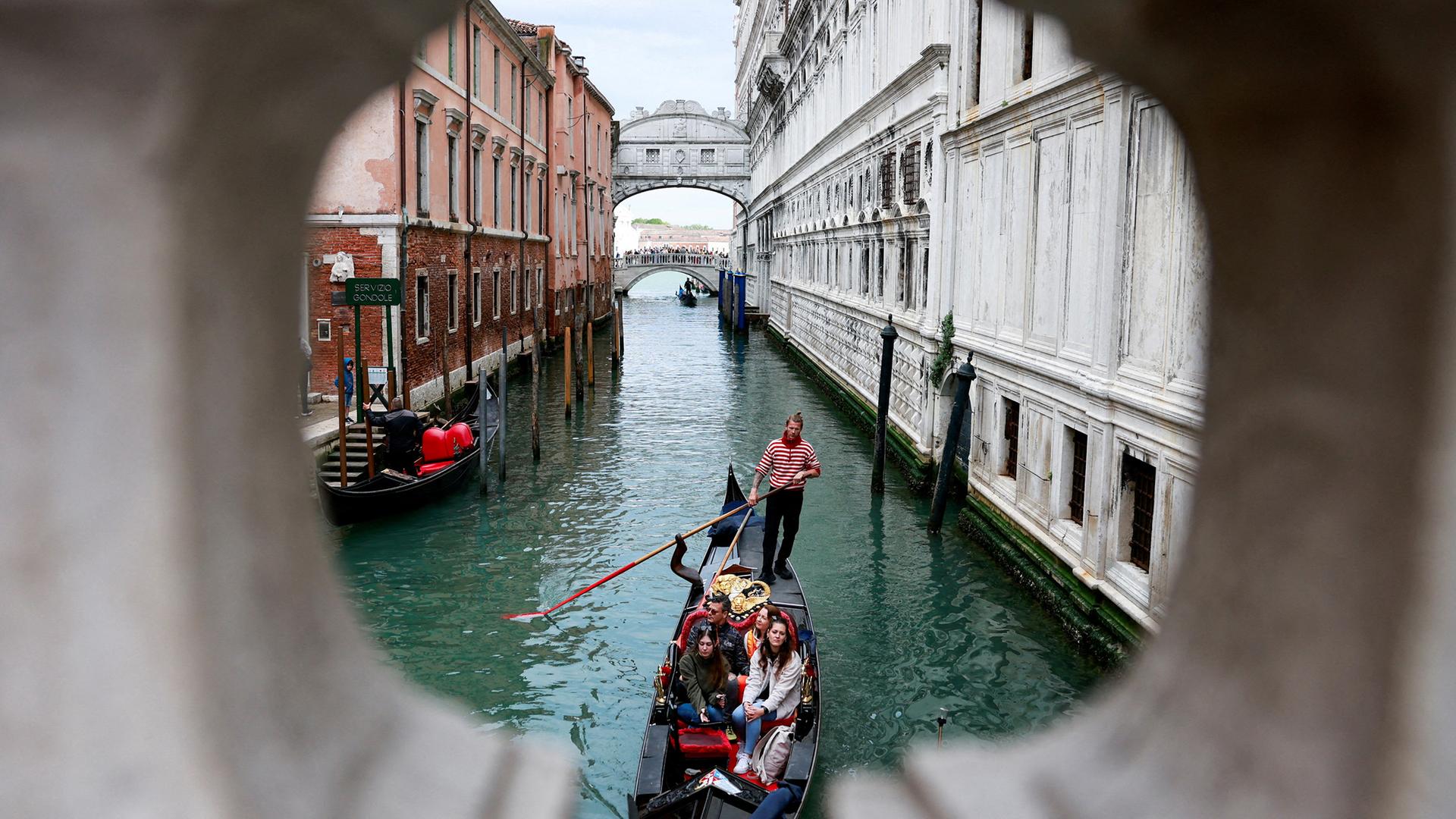 Ein Gondoliere rudert seine Gondel durch den Kanal von Venedig