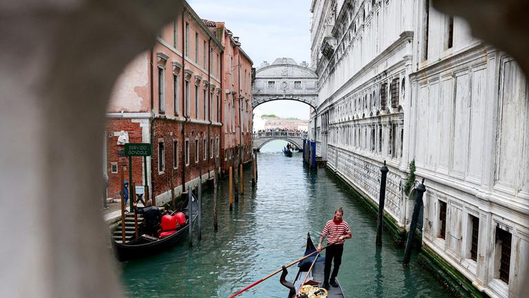 Ein Gondoliere rudert seine Gondel durch den Kanal von Venedig