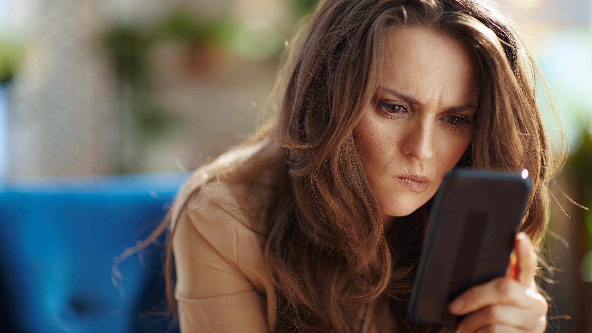 Frau blickt angestrengt auf Smartphone