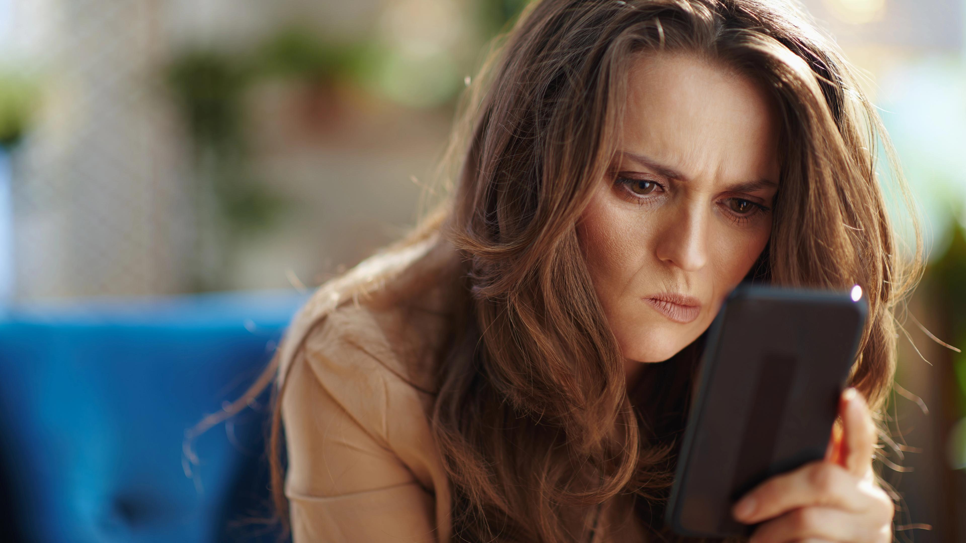 Frau blickt angestrengt auf Smartphone