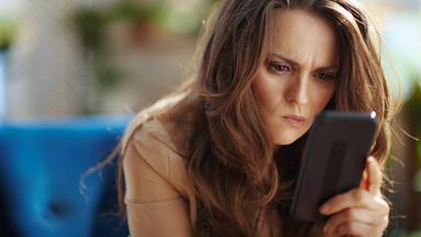 Frau blickt angestrengt auf Smartphone