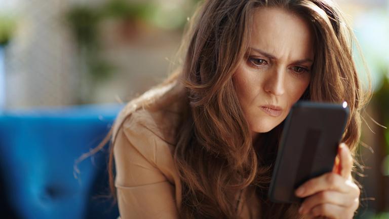 Frau blickt angestrengt auf Smartphone