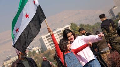 Zwei Mädchen mit syrischer Fahne zeigen mit den Daumen nach oben