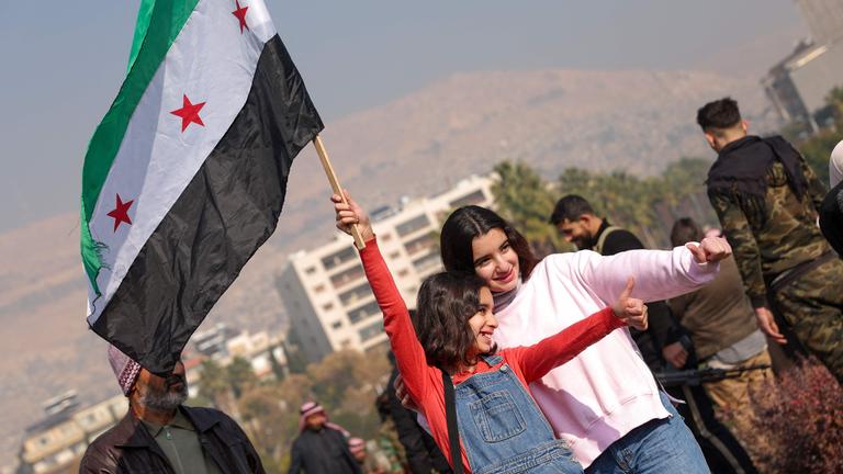 Zwei Mädchen mit syrischer Fahne zeigen mit den Daumen nach oben