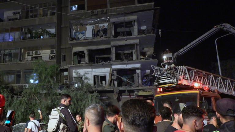 Syrische Soldaten und Menschen begutachten die Schäden nach dem Einschlag von Raketen auf das Gebäude im Viertel Al-Mazzeh in Damaskus