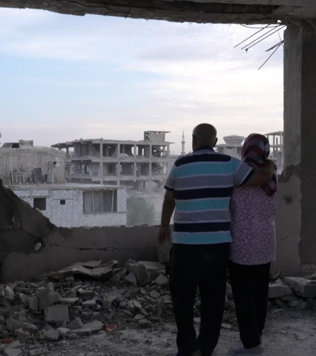 Ein Mann und eine Frau stehen Arm in Arm in Syrien, Damaskus ihrem zertstörten Haus.