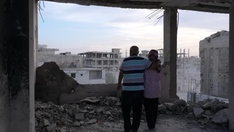 Ein Mann und eine Frau stehen Arm in Arm in Syrien, Damaskus ihrem zertstörten Haus.