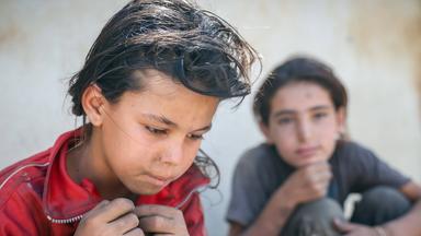 Zwei syrische Mädchen in zerlumpten Kleidern sitzen am Straßenrand, nachdem sie am 02.09.2025 Müll nach Plastikresten durchsucht haben, die sie verkaufen können, um ihre Familie in Damaskus zu unterstützen.