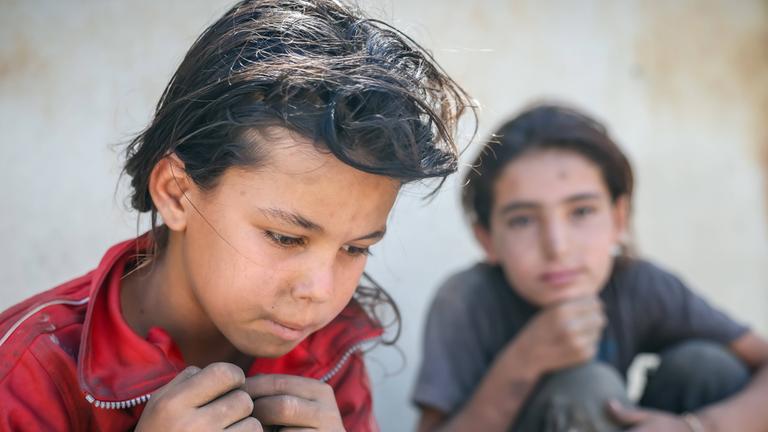 Zwei syrische Mädchen in zerlumpten Kleidern sitzen am Straßenrand, nachdem sie am 02.09.2025 Müll nach Plastikresten durchsucht haben, die sie verkaufen können, um ihre Familie in Damaskus zu unterstützen.