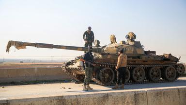 Soldaten untersuchen einen zurückgelassenen Panzer der syrischen Armee in Aleppo, Syrien.