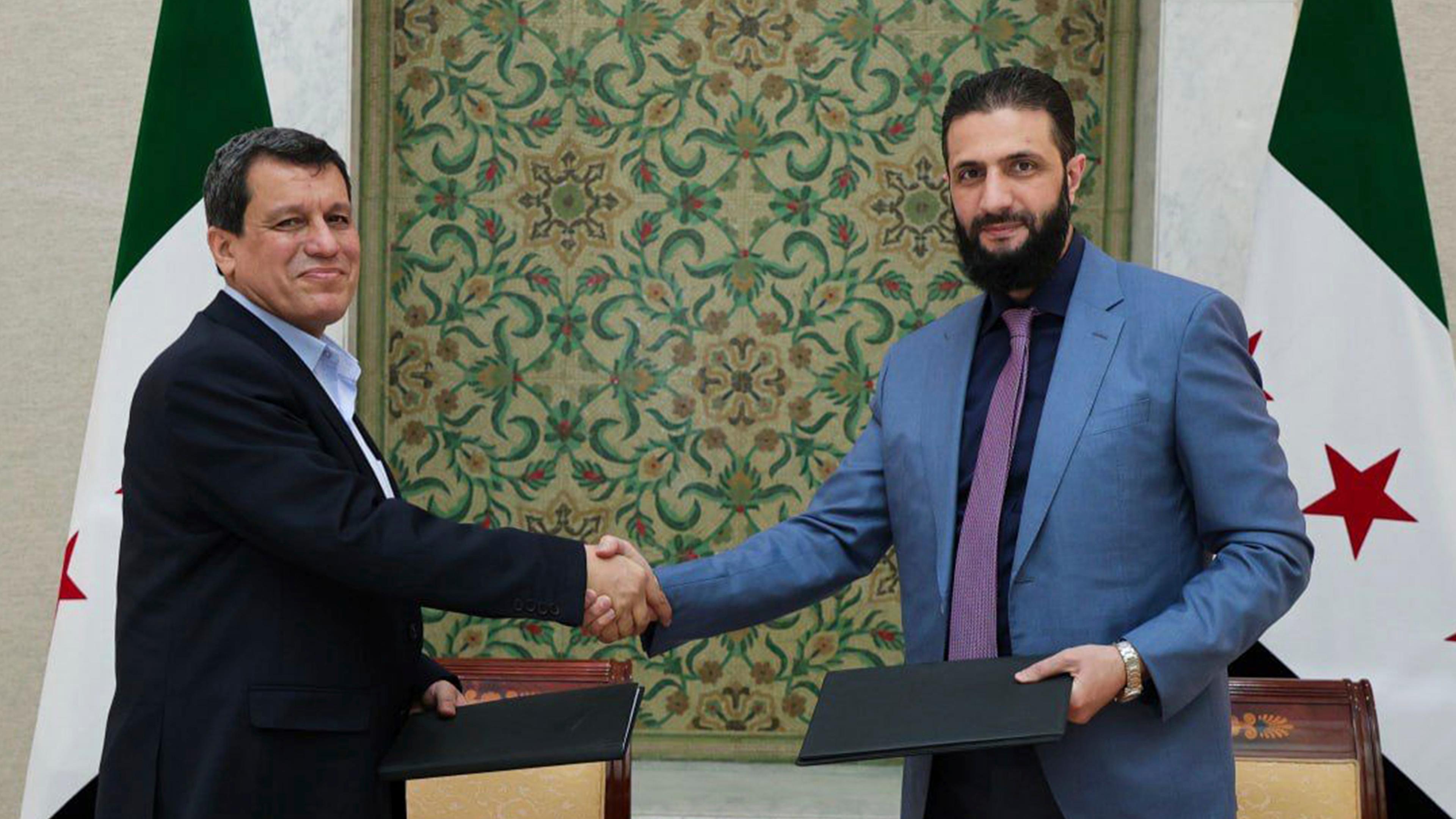 SDF-Oberkommandeur Mazloum Abdi und Ahmed al-Sharaa, Präsident der Übergangsregierung, geben sich die Hand.