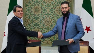 SDF-Oberkommandeur Mazloum Abdi und Ahmed al-Sharaa, Präsident der Übergangsregierung, geben sich die Hand.