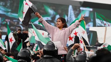 Menschen schwenken syrische Flaggen bei einer Feier zum ersten Jahrestag des Sturzes des ehemaligen Präsidenten Baschar al-Assad in Damaskus, Syrien, am Montag, dem 8. Dezember 2025.