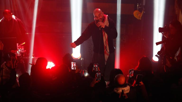 Der syrische Rapper "Al Darwish" auf der Bühne mit roten Scheinwerfern.