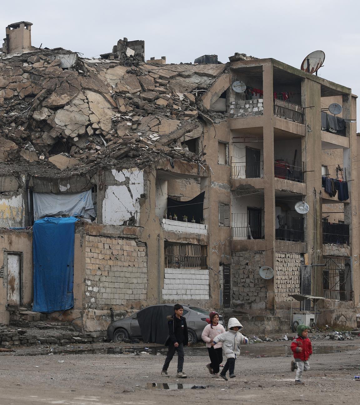 Kinder gehen an einem beschädigten Wohngebäude in Raqqa, Syrien, vorbei.