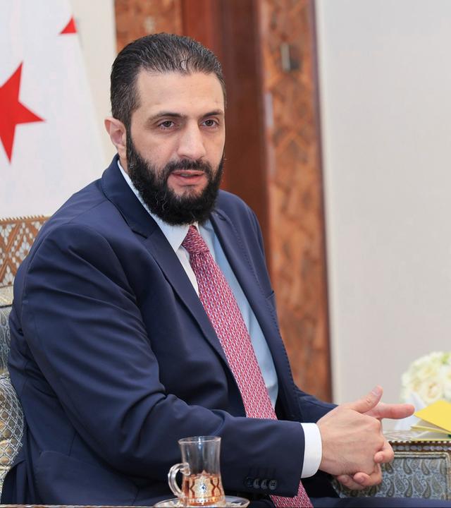 27.07.2025, Syrien, Damaskus: Auf diesem von der amtlichen syrischen Nachrichtenagentur SANA via AP veröffentlichten Foto erhält der syrische Interimspräsident Ahmad al-Sharaa die endgültige Fassung des vorläufigen Wahlsystems für die Volksversammlung.