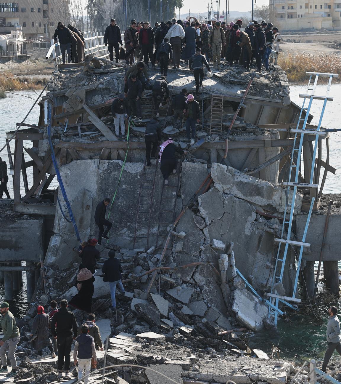 Menschen stehen auf einer zerstörten Brücke im syrischen Raqqa