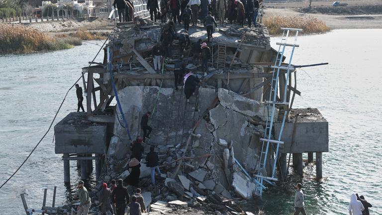 Menschen stehen auf einer zerstörten Brücke im syrischen Raqqa