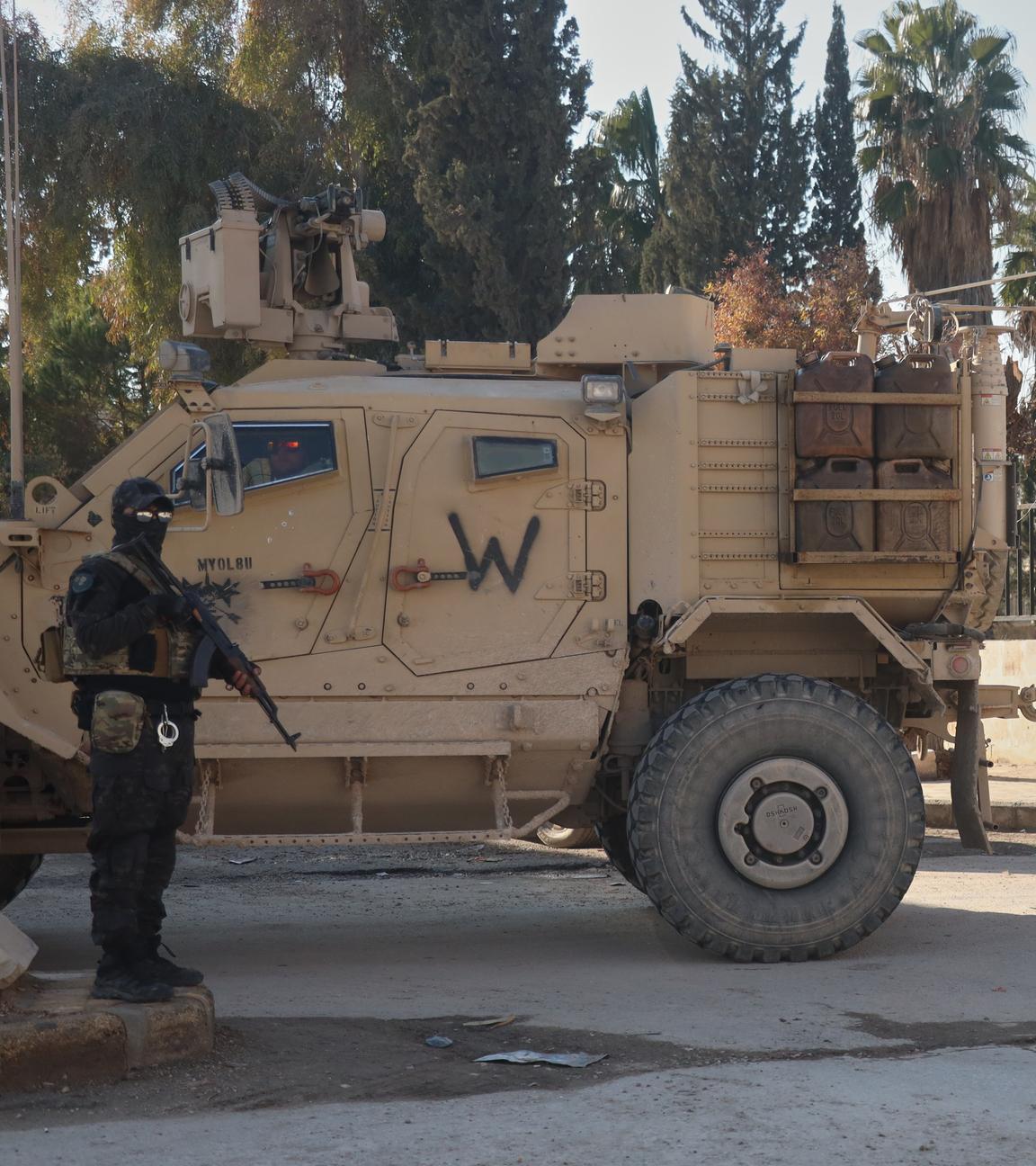 Kämpfer der Syrischen Demokratischen Kräfte (SDF) stehen in der Nähe eines US-Militärfahrzeugs der US-geführten Koalition gegen die Gruppe Islamischer Staat in Deir Hafer. 