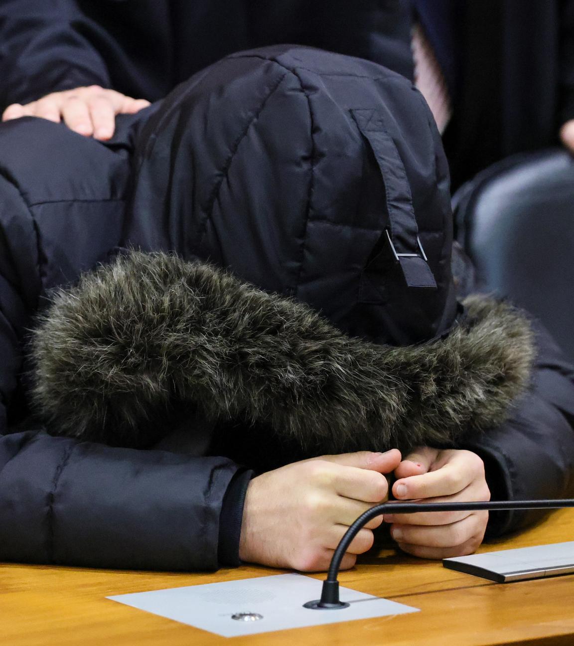 Von der Kapuze seiner Jacke bedeckt stütz der verurteilte syrische Arzt Alaa M. seinen Kopf auf die Anklagebank im Frankfurter Oberlandesgericht.