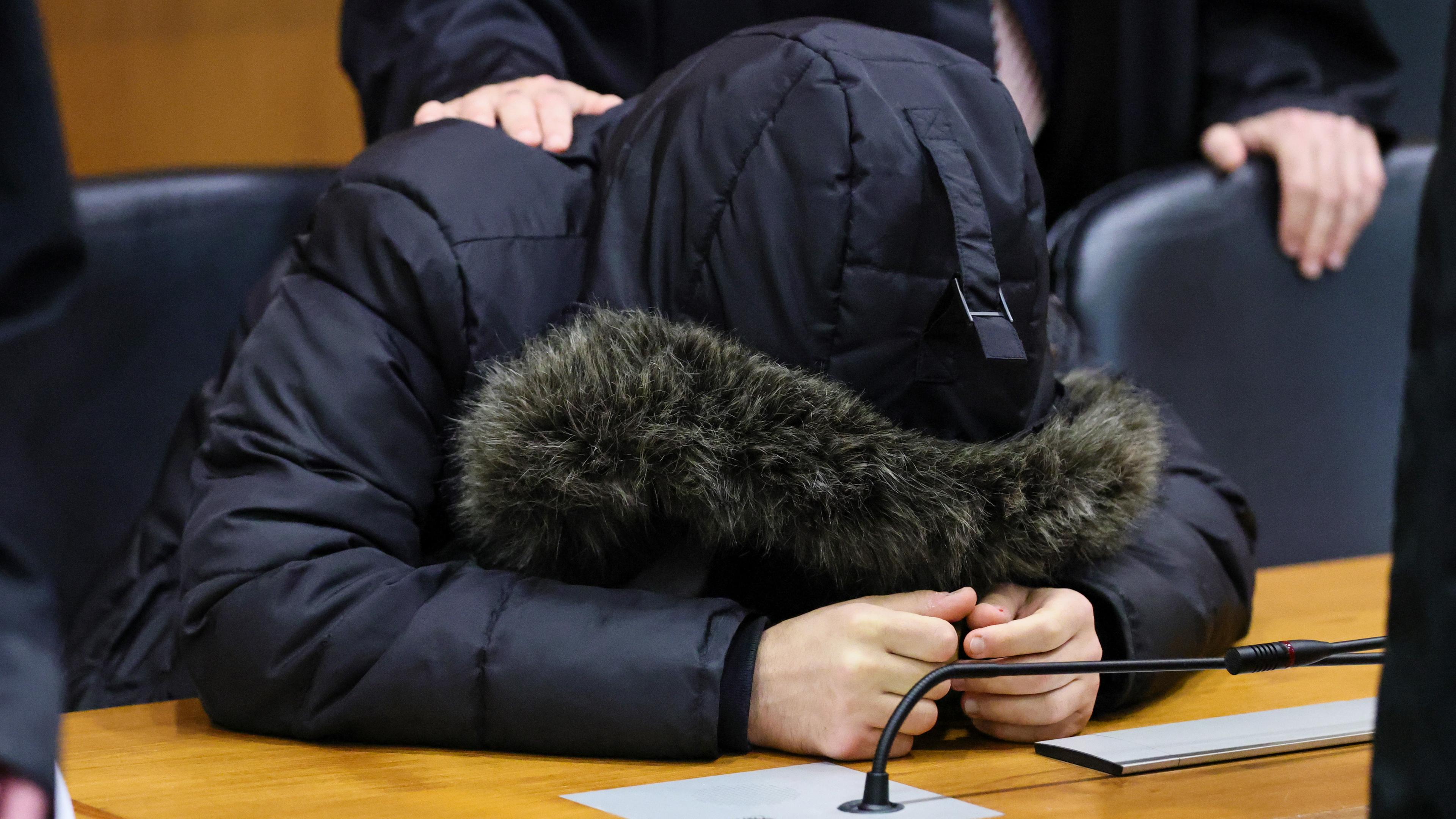 Von der Kapuze seiner Jacke bedeckt stütz der verurteilte syrische Arzt Alaa M. seinen Kopf auf die Anklagebank im Frankfurter Oberlandesgericht.