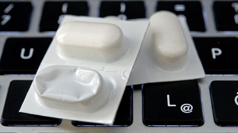 Blister mit Tabletten liegen auf einer Tastatur.