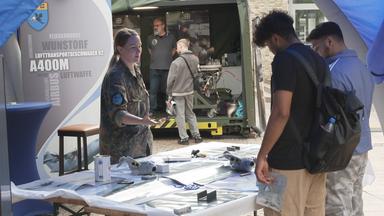 Bundeswehr-Stand mit Frau, die zwei Männern etwas zeigt
