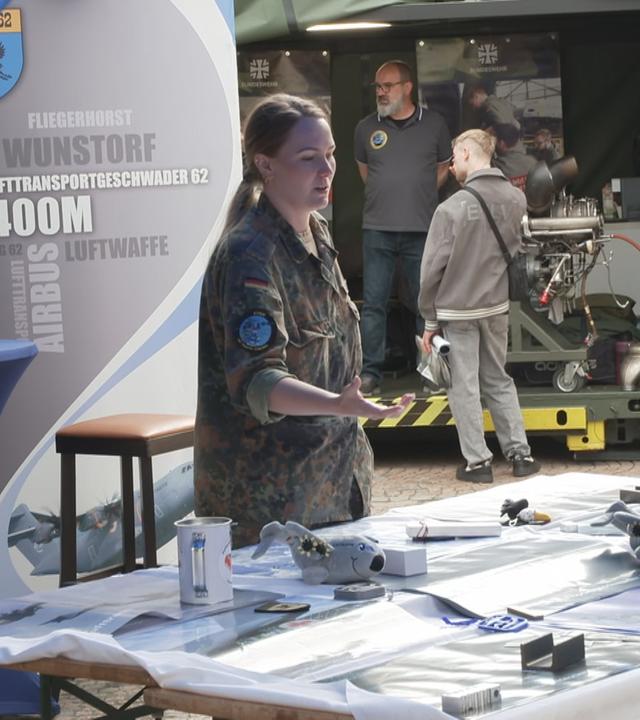 Bundeswehr-Stand mit Frau, die zwei Männern etwas zeigt