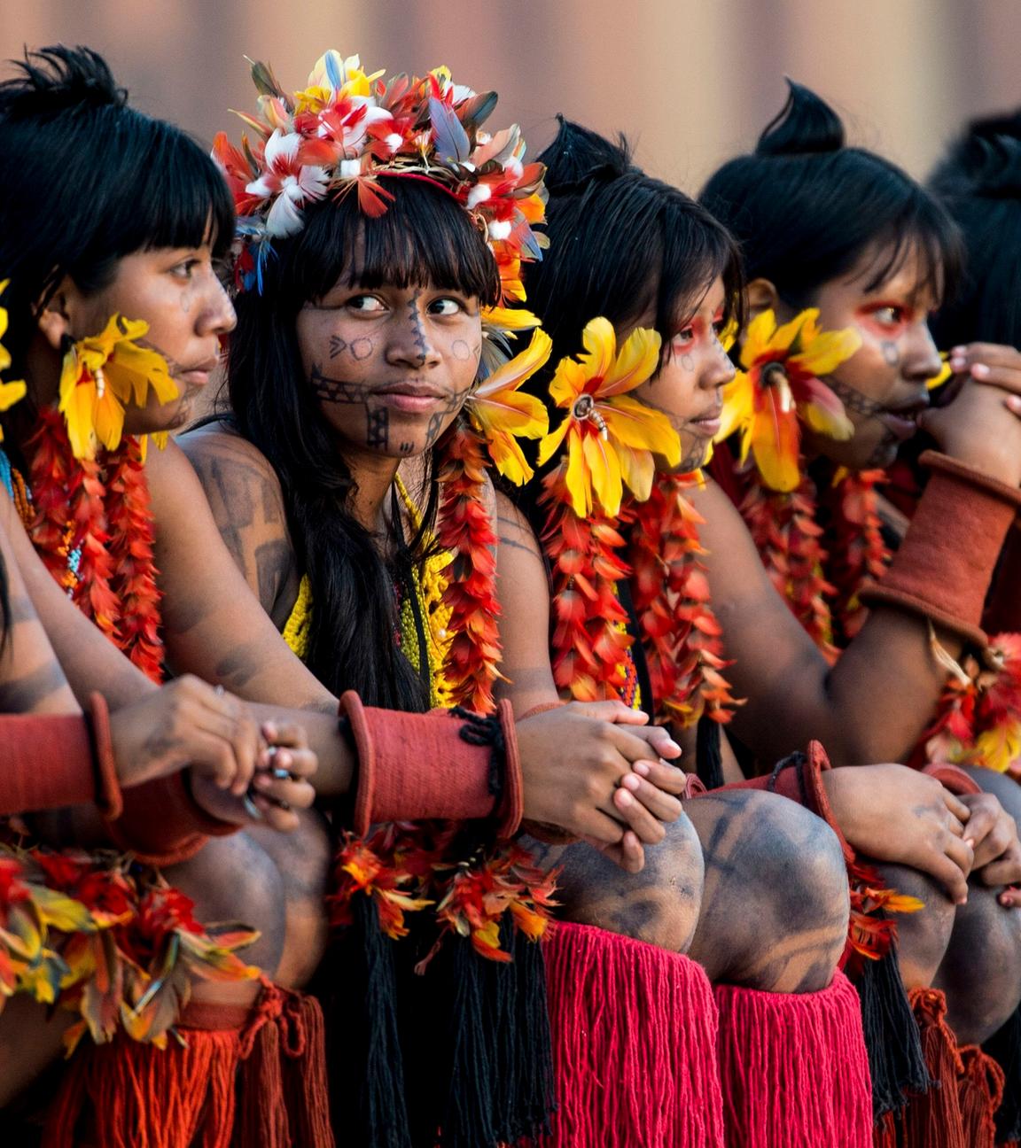 Gruppe von jungen indigenen Frauen. Sie haben sich mit Federn und Blumen geschmückt.
