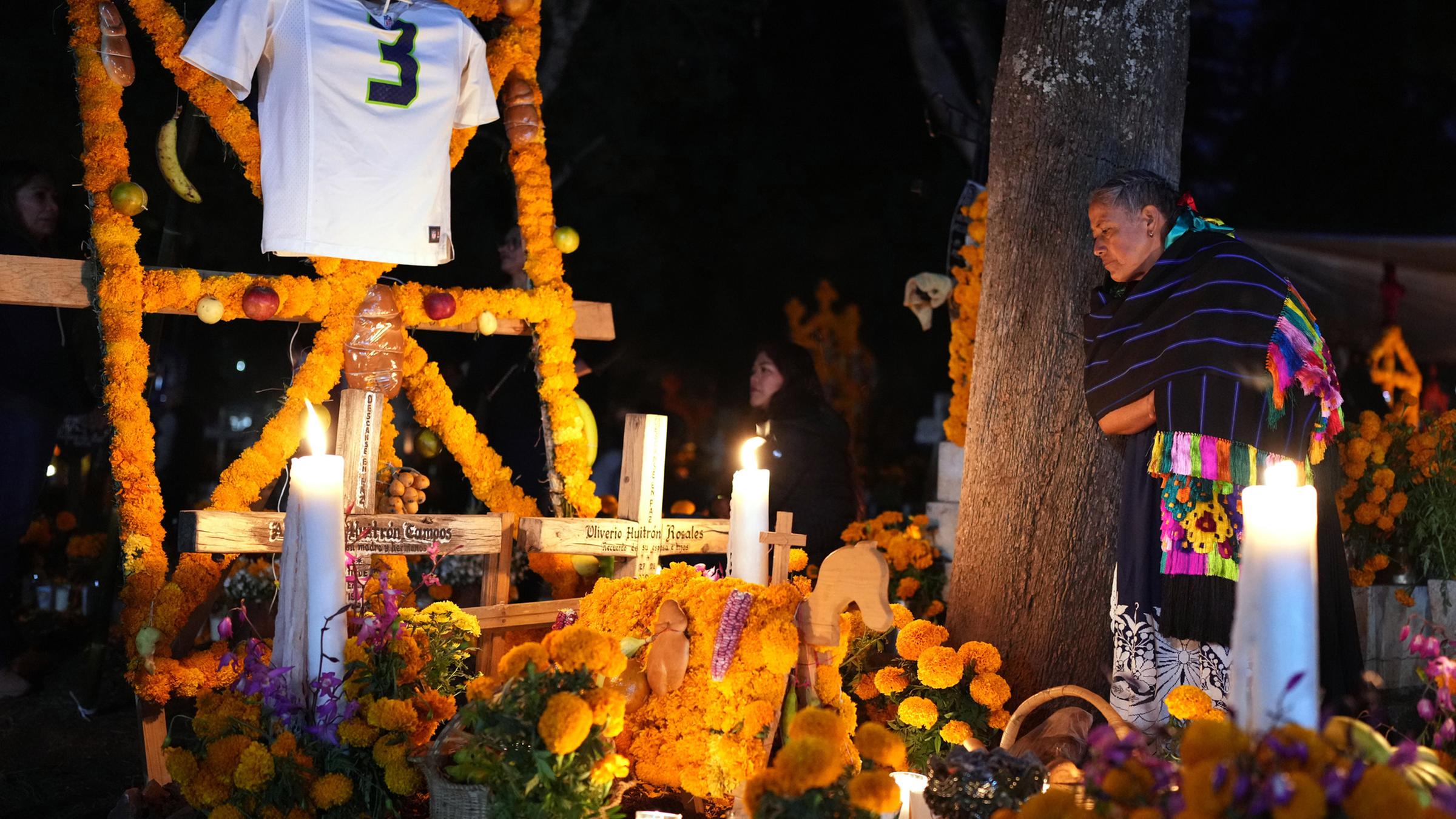 Eine Frau steht neben dem Grab eines geliebten Menschen und feiert den Tag der Toten auf dem Friedhof von Tzintzuntzan im Bundesstaat Michoacán, Mexiko, am Freitag, 31. Oktober 2025. 